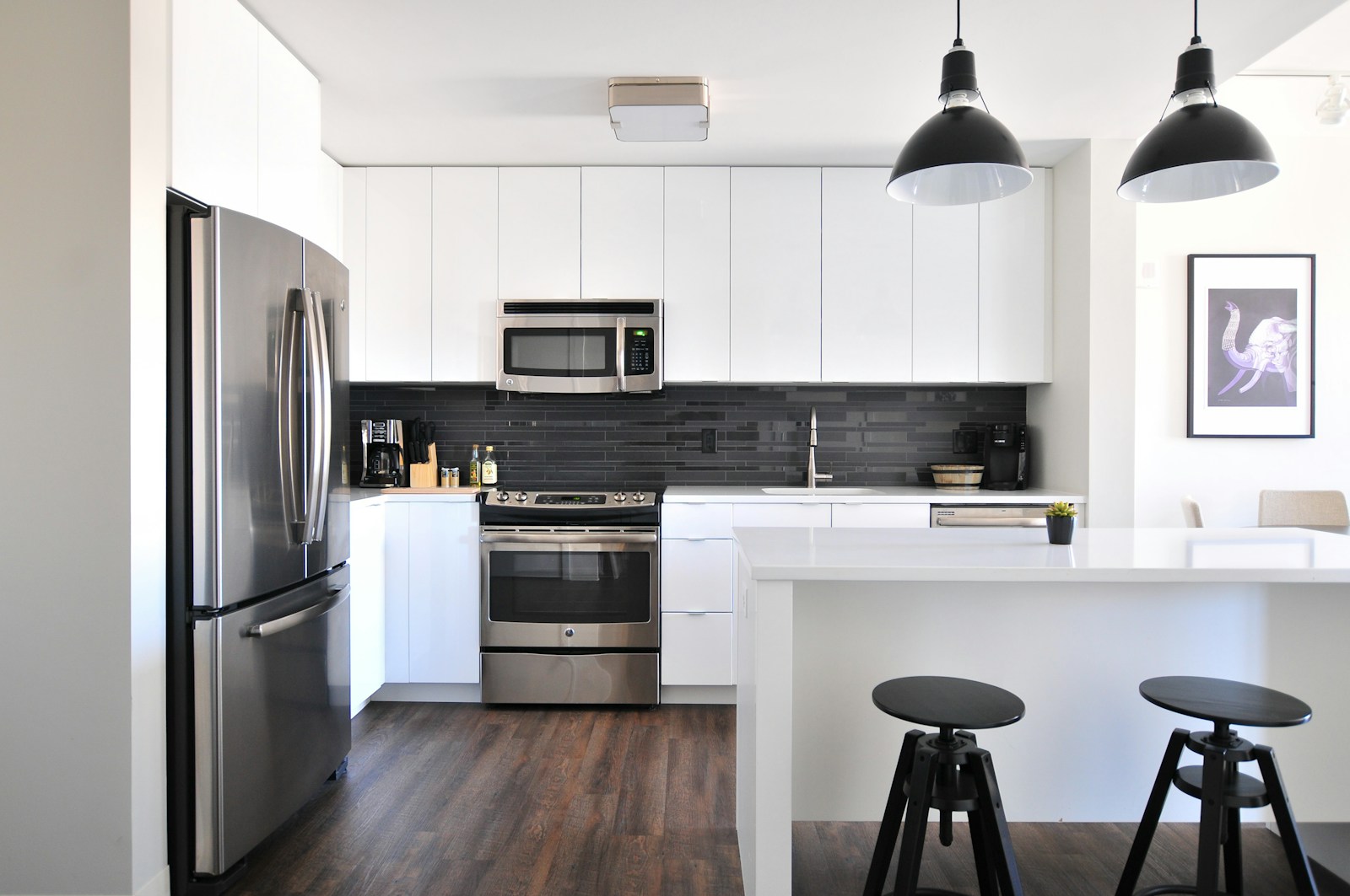 Kitchen with white cabinetry, black accents, and stainless steel fridge