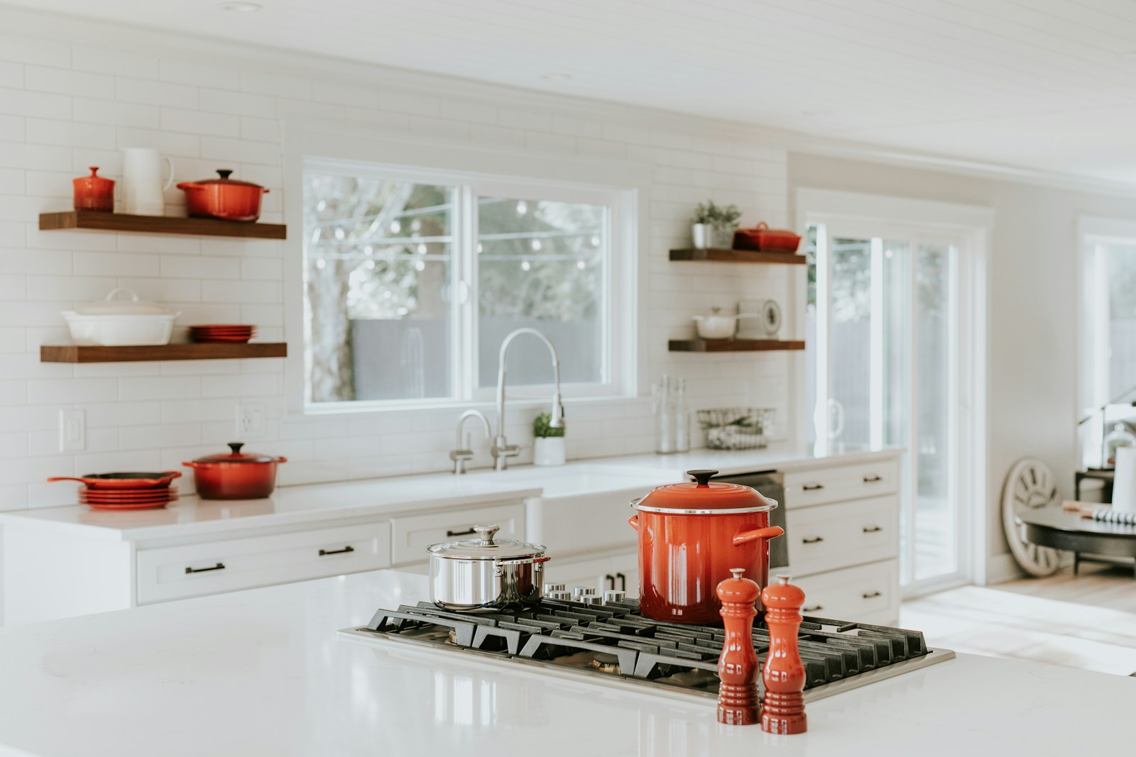 All white kitchen countertops and cabinets with built-in stovetop and red cookware